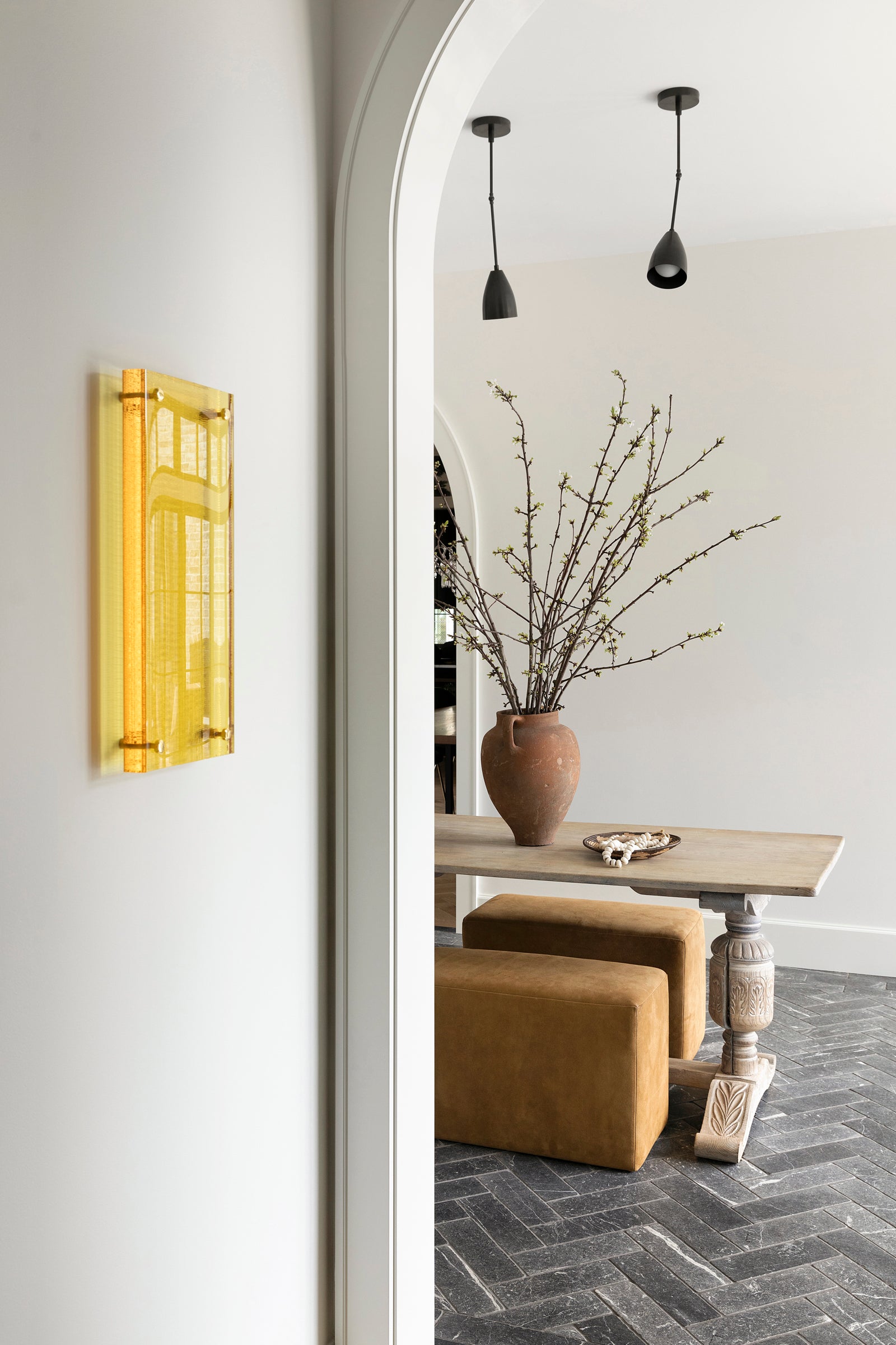 An informal sitting area with an antique table, modern pendants, and textural bench seating by Nate Berkus.