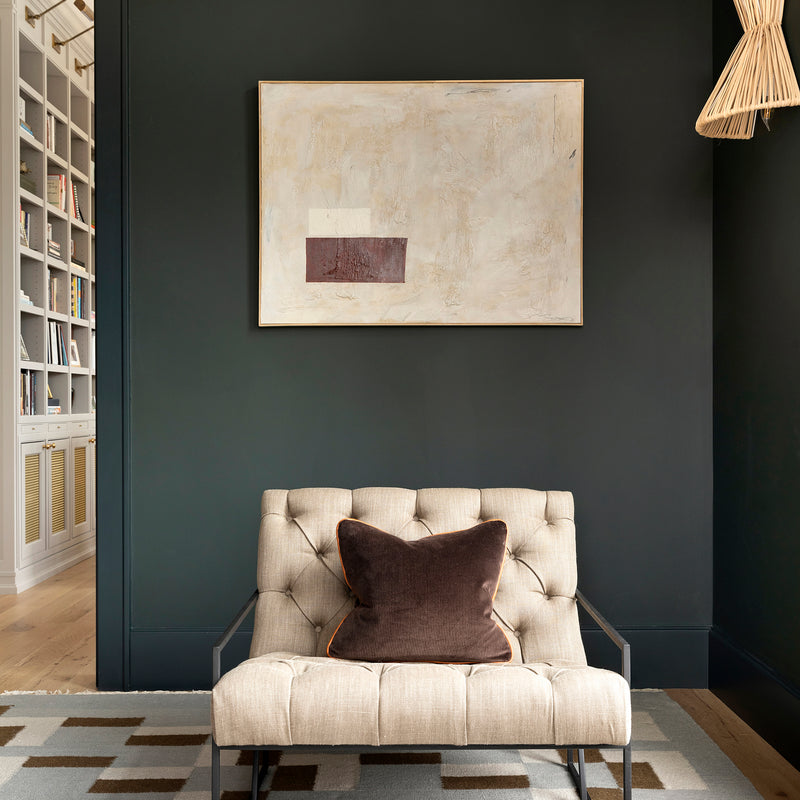 In an office designed by Nate Berkus Associates, a plush lounge chair is ensconced by deep green tones and textural artwork.