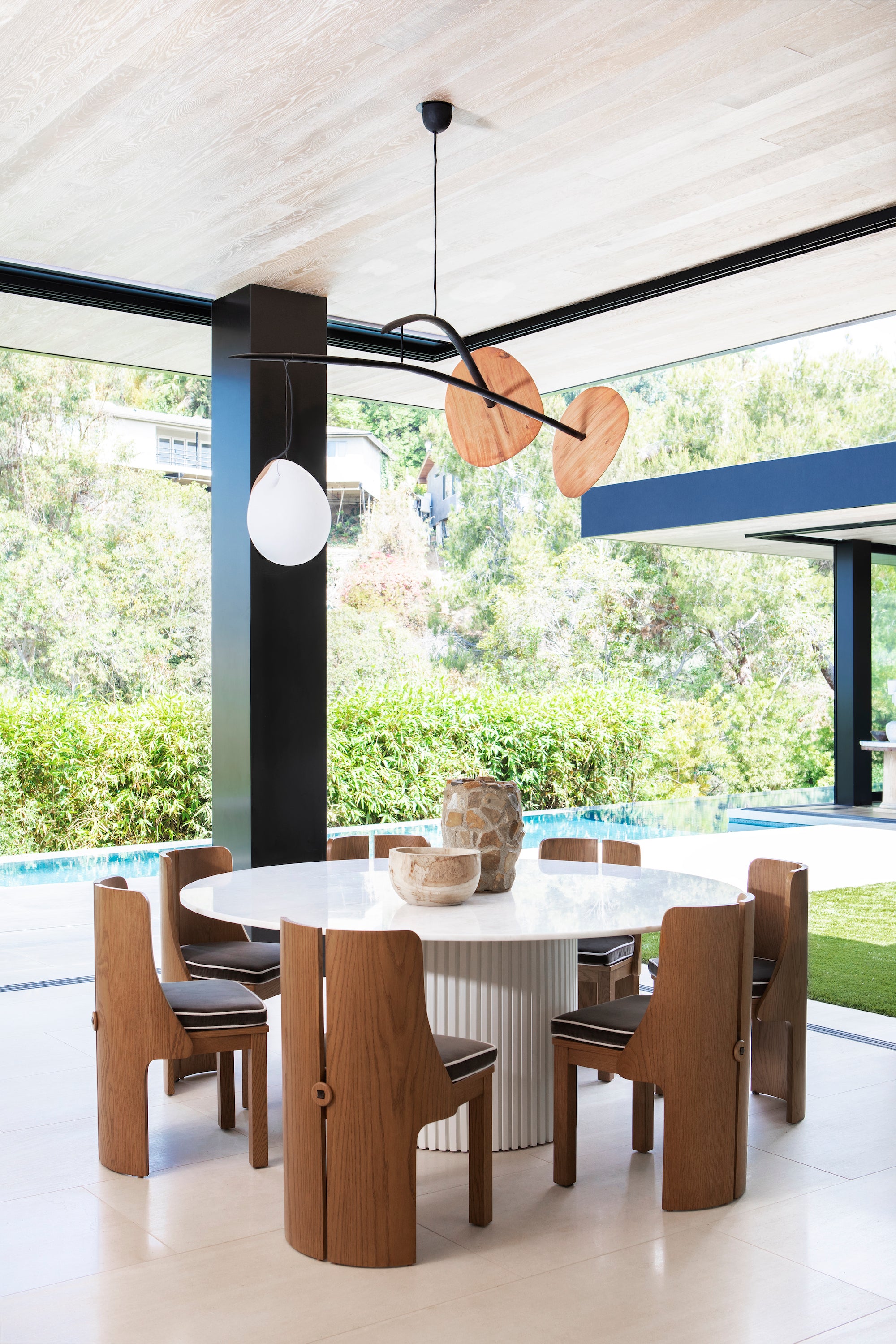 A modern dining area with unique bentwood chairs and artful lighting, designed by Nate Berkus Associates.