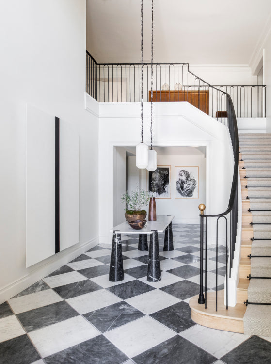 An open and airy entryway of checkered tile and statement pendant lighting, designed by Nate Berkus Associates and Jeremiah Brent.