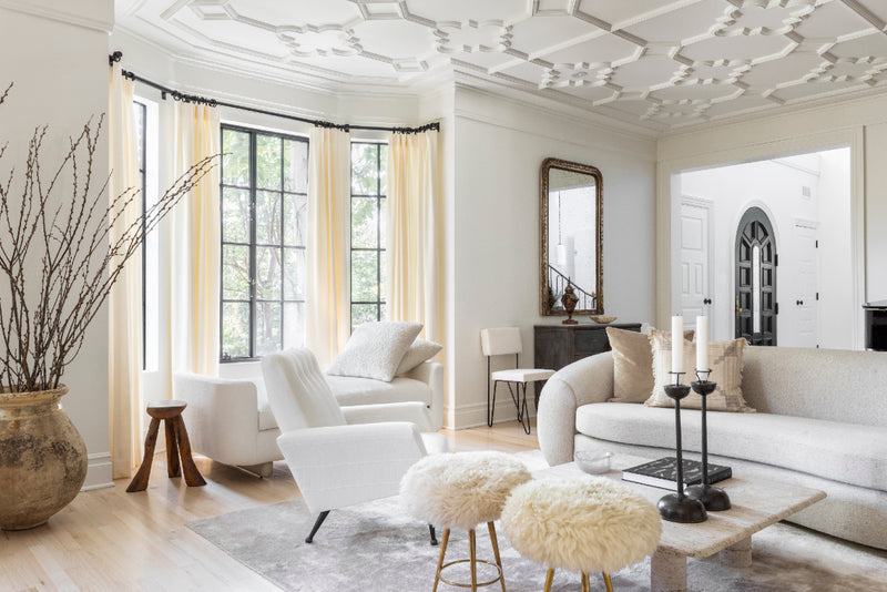 A tonal white living area with ornate ceiling mouldings in an estate designed by Nate Berkus and Jeremiah Brent.