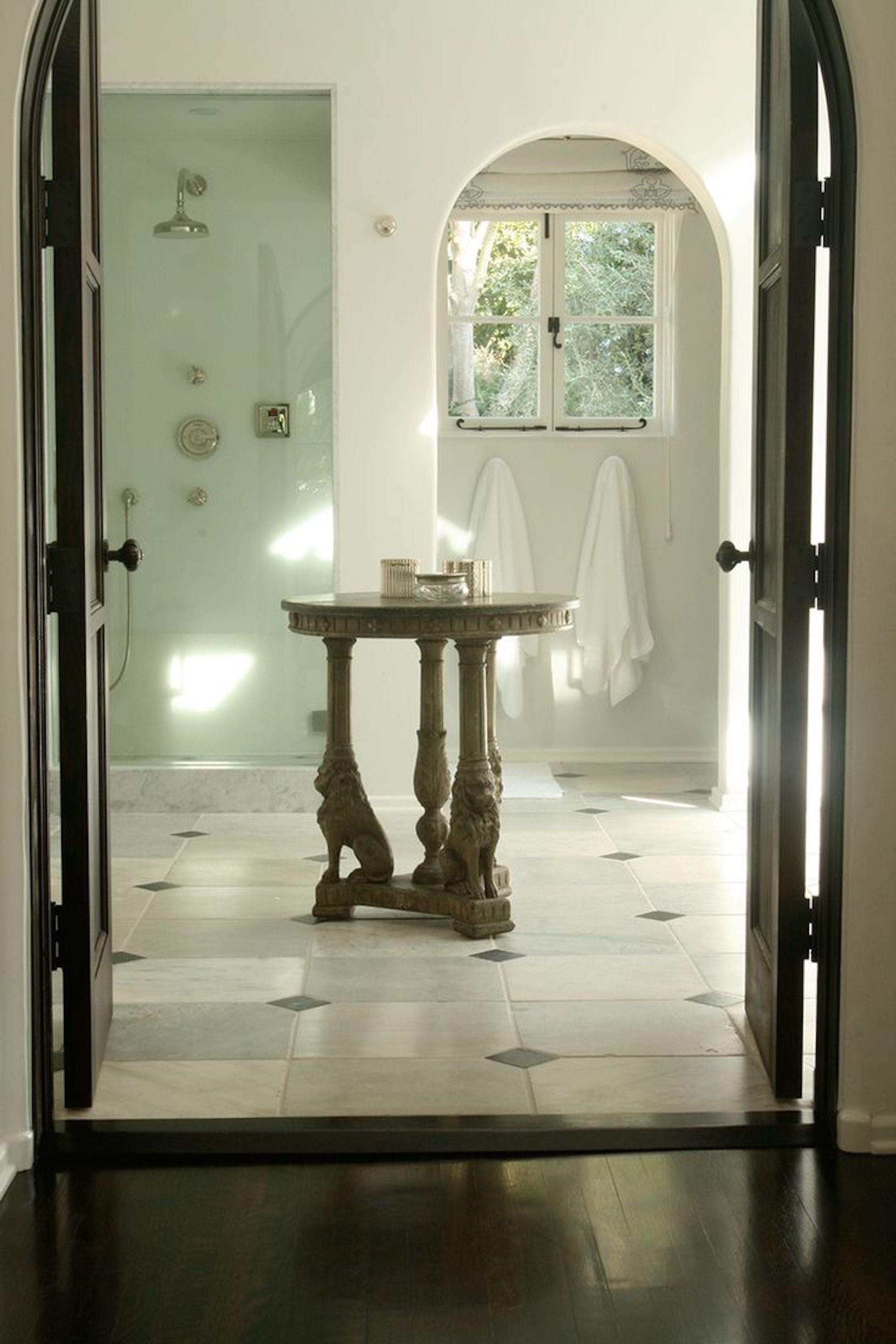 A textural white-on-white bathroom by Nate Berkus Associates featuring arched entries and natural stone.