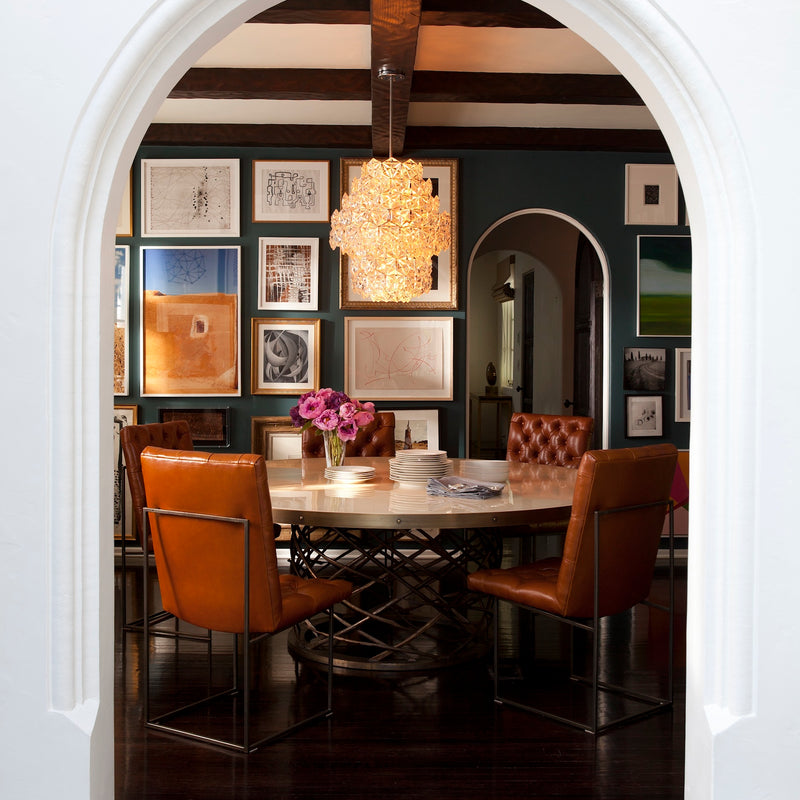 An arched entryway leads to a moody and layered dining space in a Los Angeles home by Nate Berkus Associates.