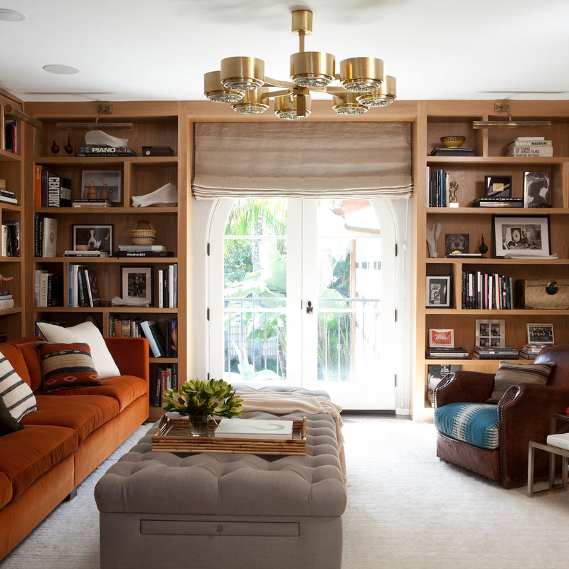 A warm home library with built-in shelving and statement lighting, designed by Nate Berkus Associates.