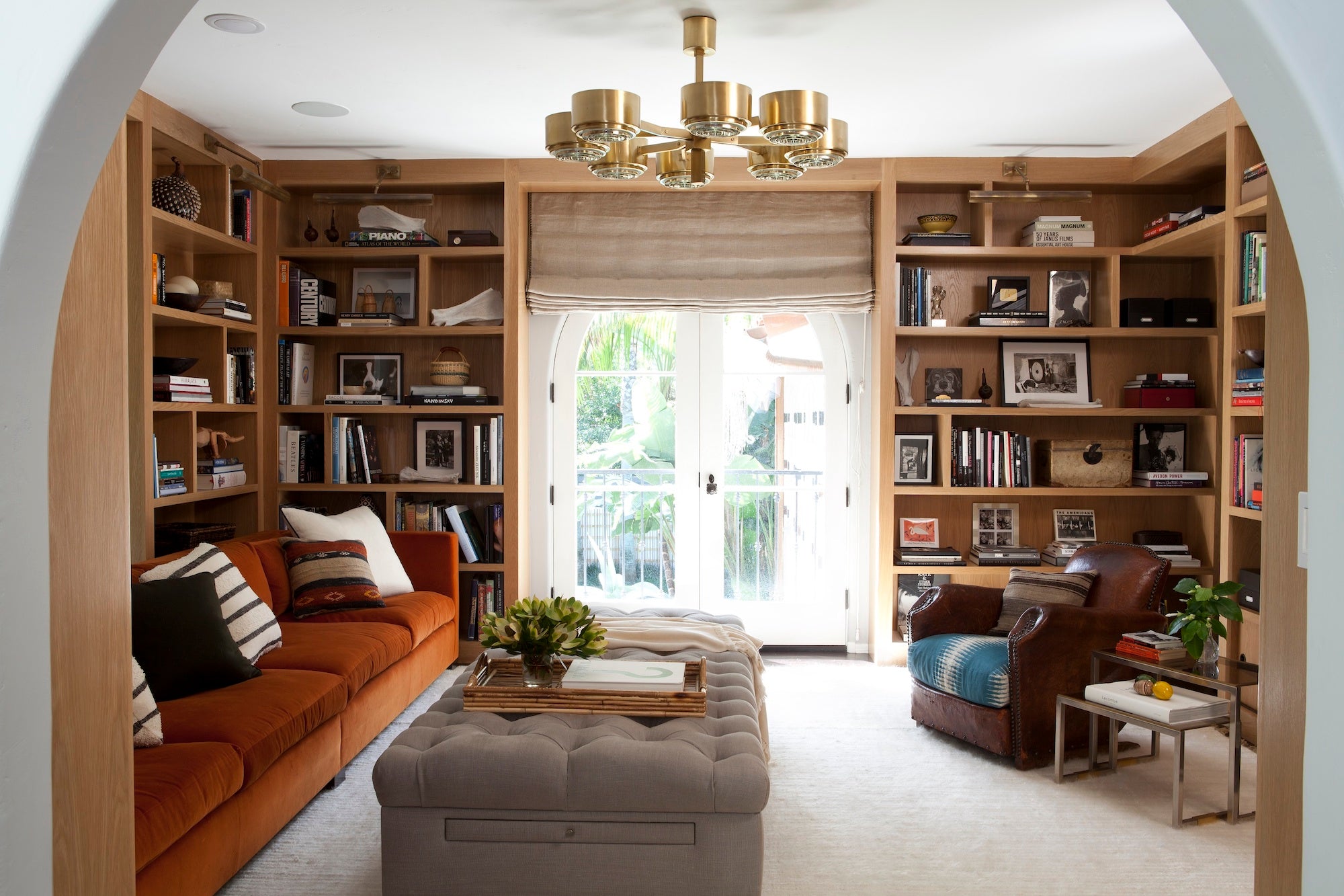 A warm home library with built-in shelving and statement lighting, designed by Nate Berkus Associates.