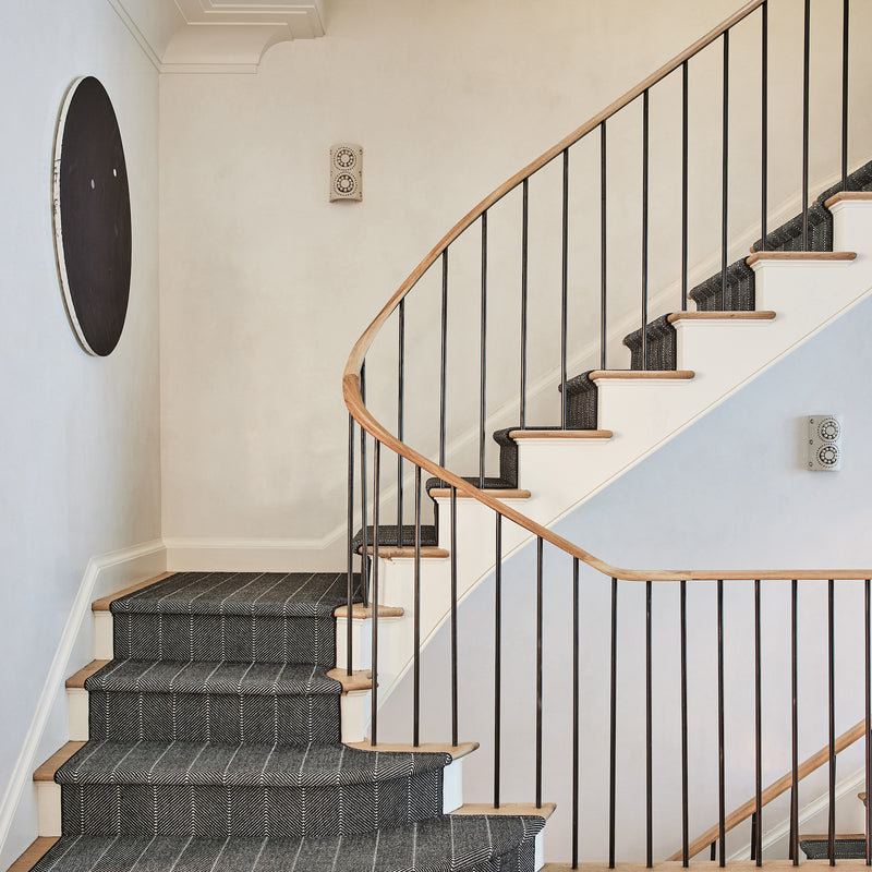 A modern staircase with a striped runner and clean lines, designed by Nate Berkus and Jeremiah Brent for their home in New York.