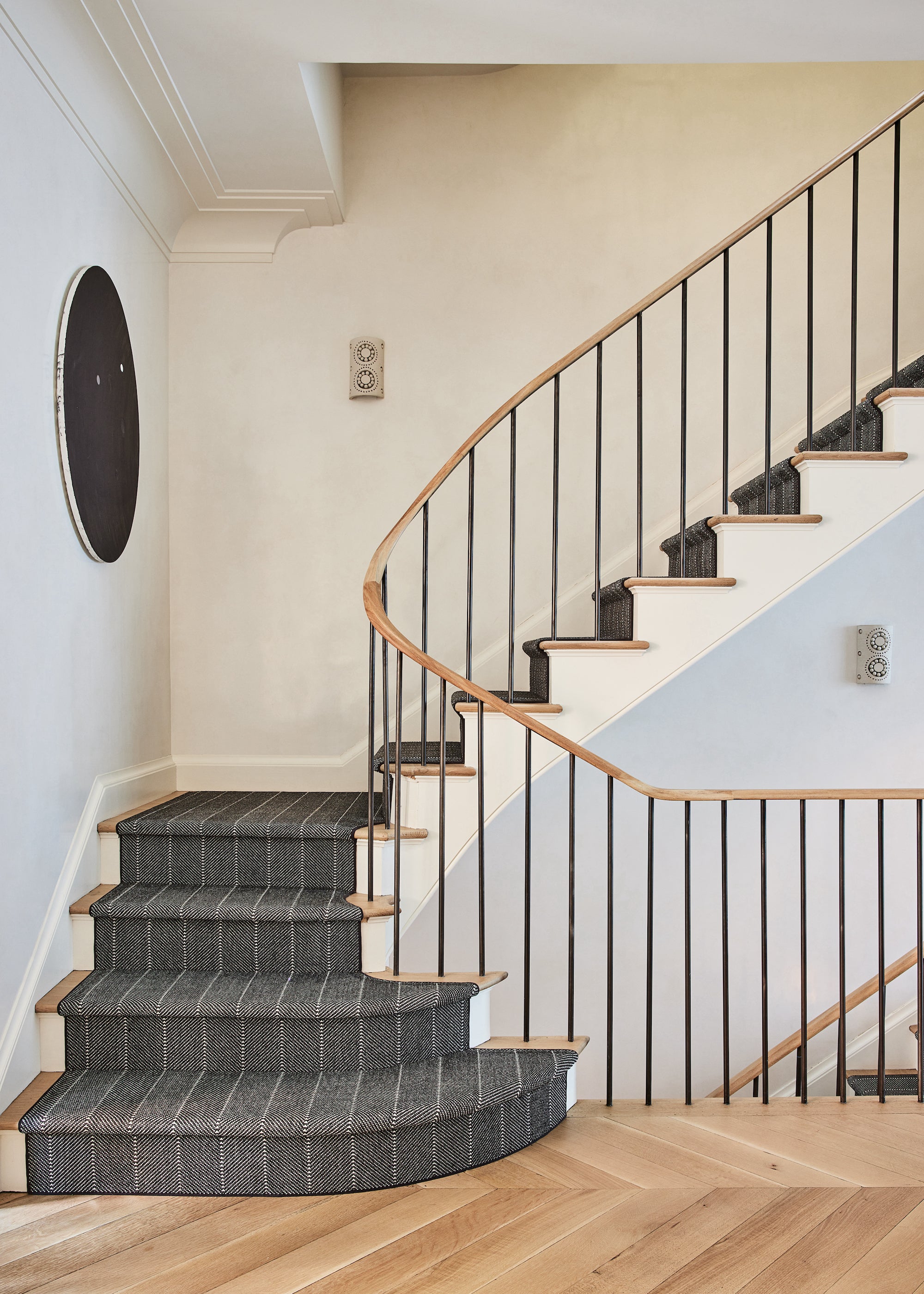 A modern staircase with a striped runner and clean lines, designed by Nate Berkus and Jeremiah Brent for their home in New York.