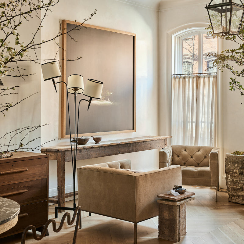 A thoughtfully curated parlor by Nate Berkus and Jeremiah Brent, featuring antique and vintage furnishings, an oversized piece of art, and indoor plants. 