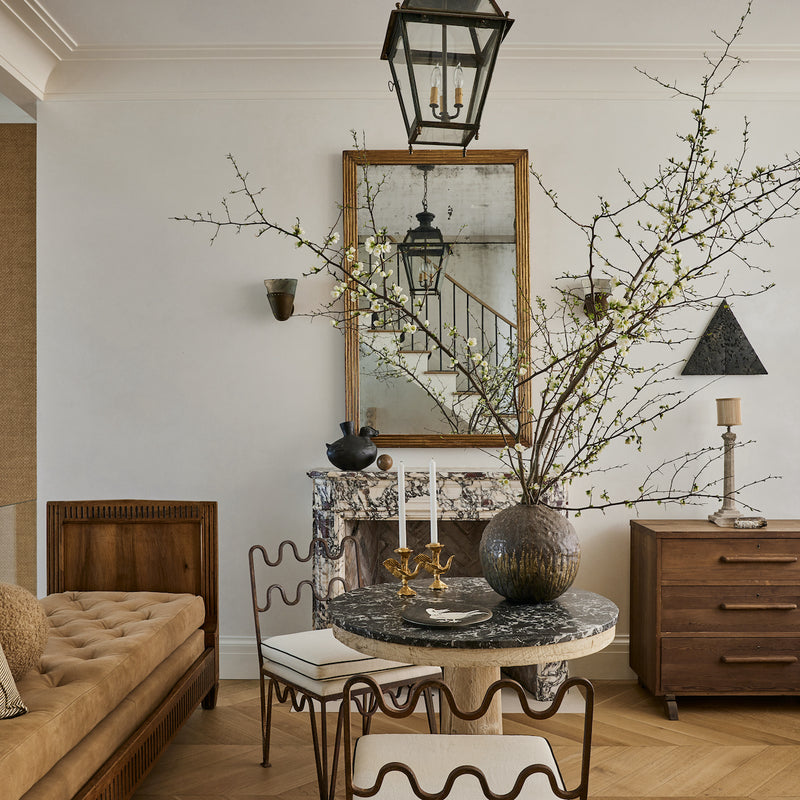 A West Village Brownstone parlor by Nate Berkus and Jeremiah Brent, featuring an original marble fireplace, sculptural furnishings, and herringbone floors.