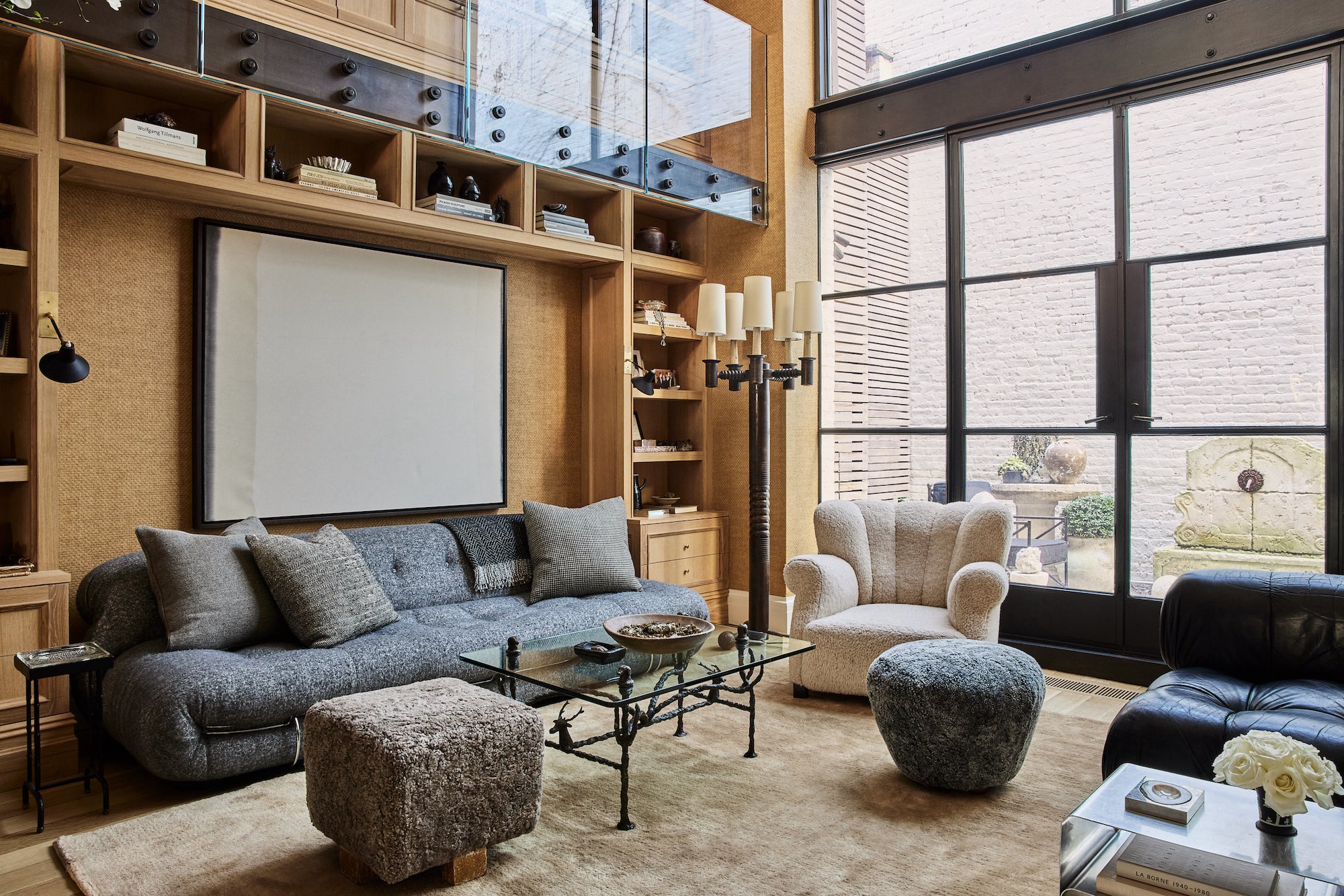 A West Village home living room with floor-to-ceiling built-ins and large-scale glass doors, designed by Nate Berkus and Jeremiah Brent.