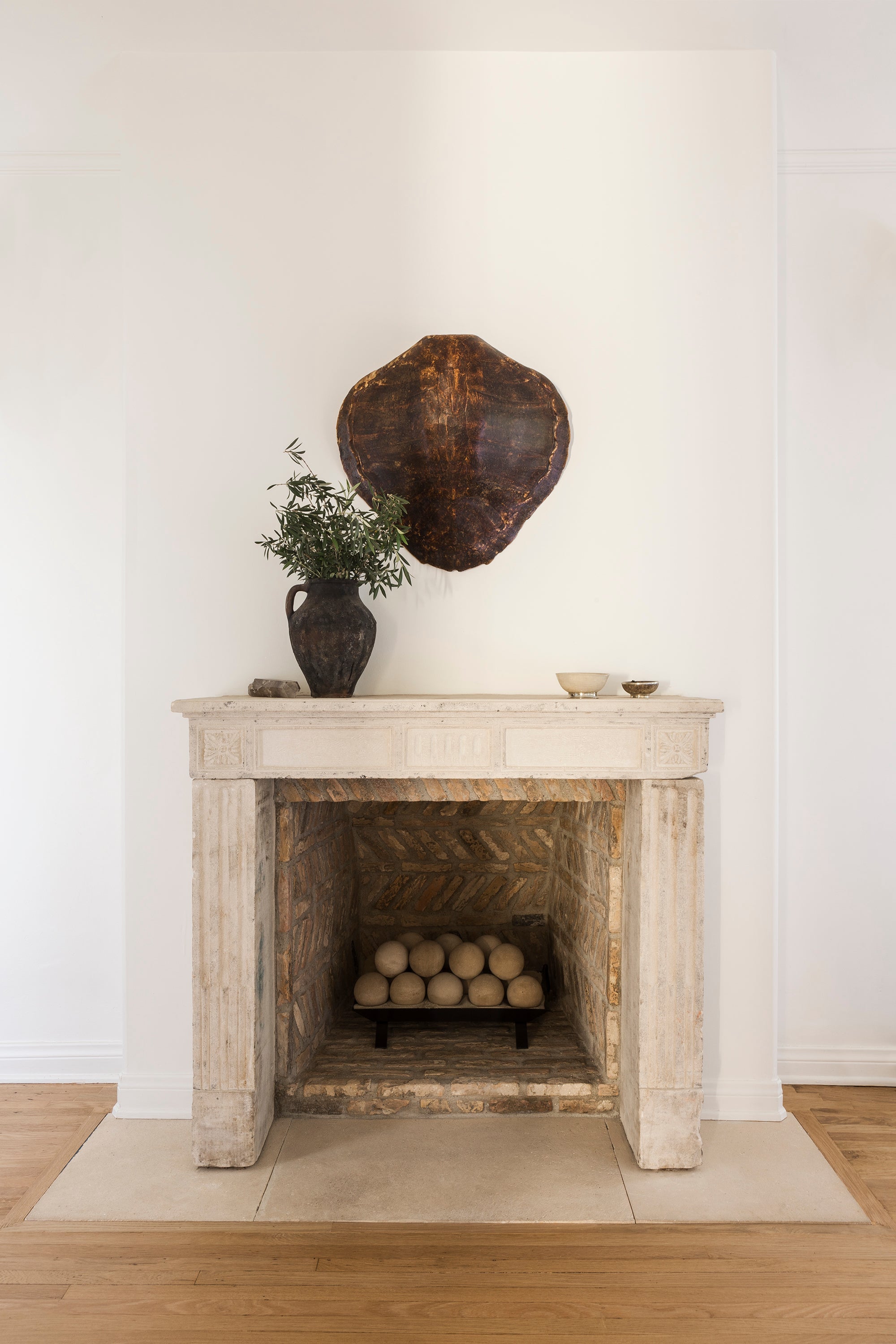 One of many original fireplaces in Nate Berkus and Jeremiah Brent's Hancock Park home, this one in shades of worn beige and styled with earthen pottery.