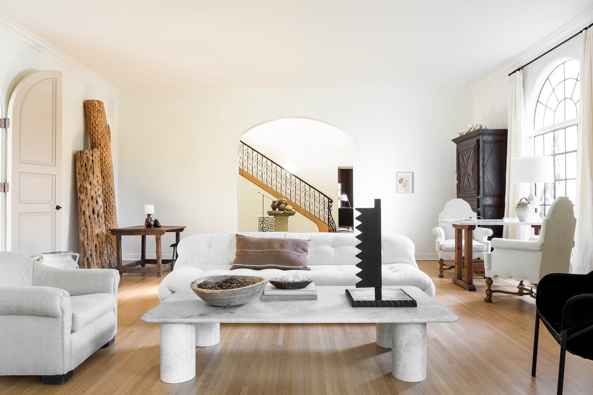 A bright and airy living area furnished with antiques and sculptural pieces, designed by Nate Berkus Associates.