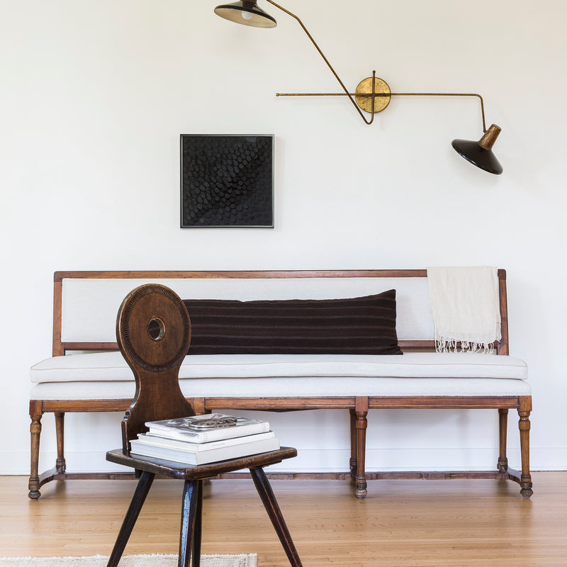A sitting area in Nate Berkus and Jeremiah Brent's 1928 Spanish colonial showcases an antique chair next to a clean-lined sofa and modern sconce lighting.