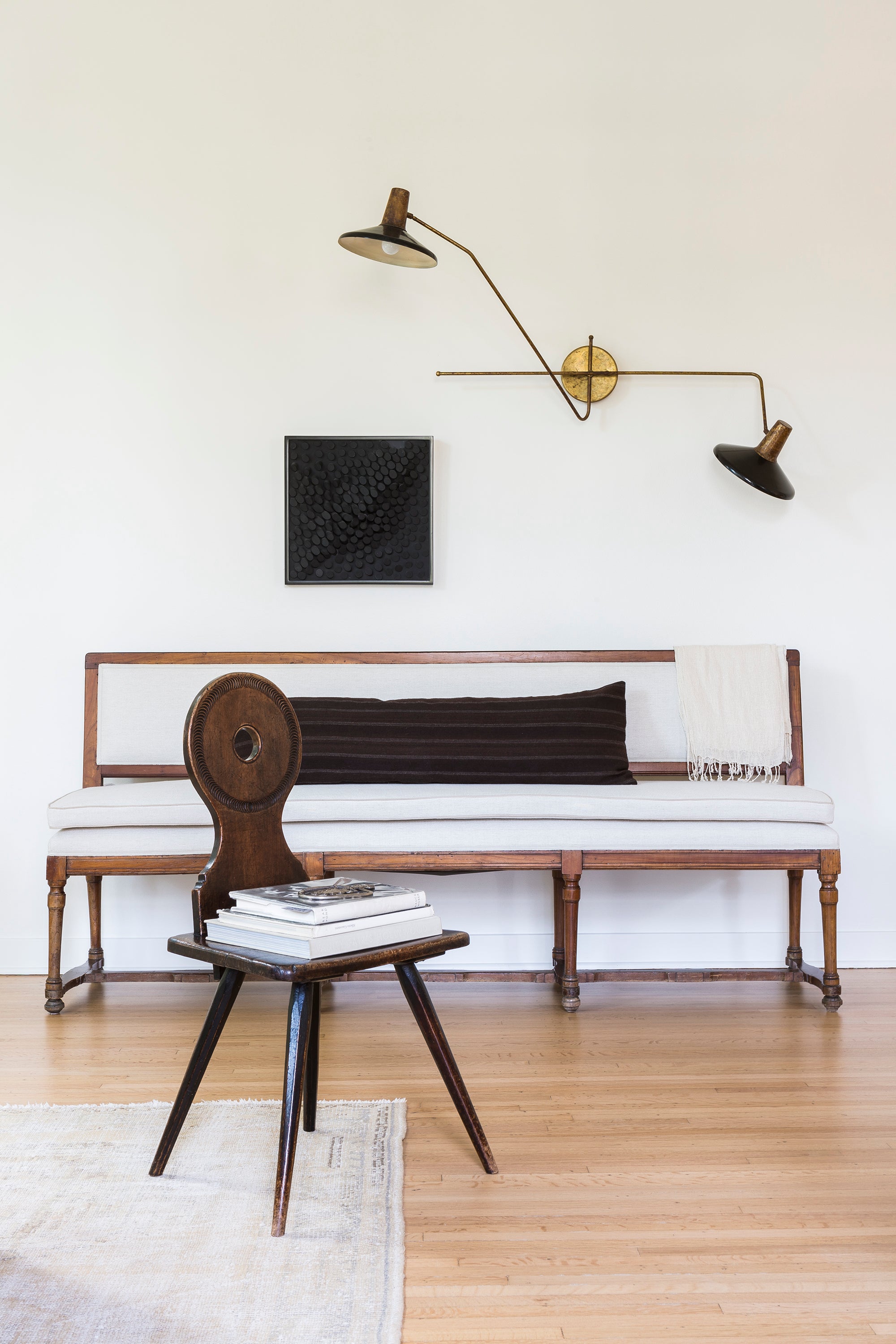 A sitting area in Nate Berkus and Jeremiah Brent's 1928 Spanish colonial showcases an antique chair next to a clean-lined sofa and modern sconce lighting.