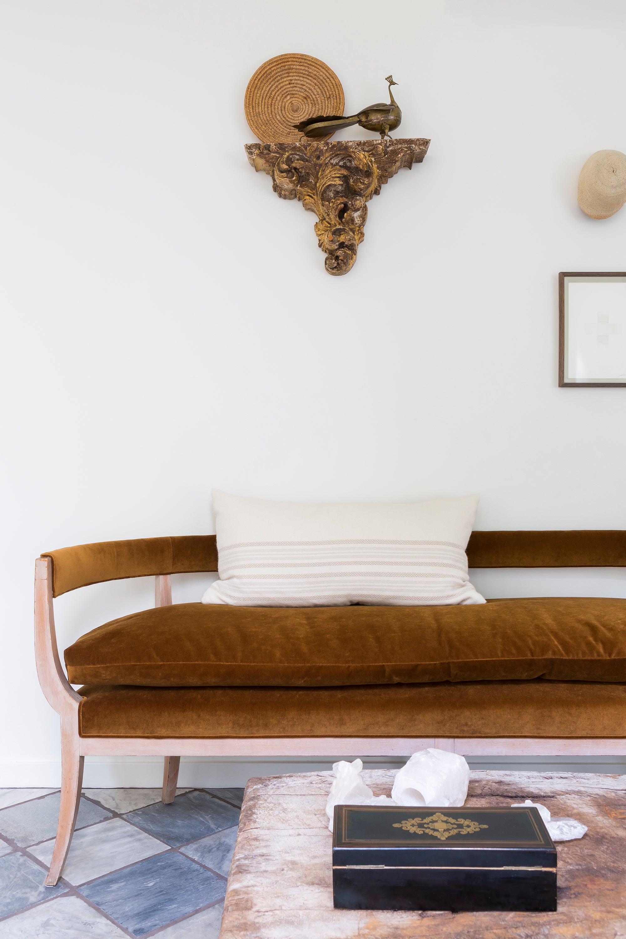 A rust-toned settee is right at home amid well-traveled finds in the entry way of the 1928 Spanish Bungalow restored and designed by Nate Berkus and Jeremiah Brent.