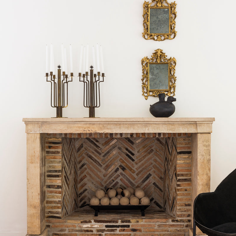 A pair of candelabras and a pair of mirrors sit above a rustic fireplace in Nate Berkus and Jeremiah Brent's Hancock Park estate.