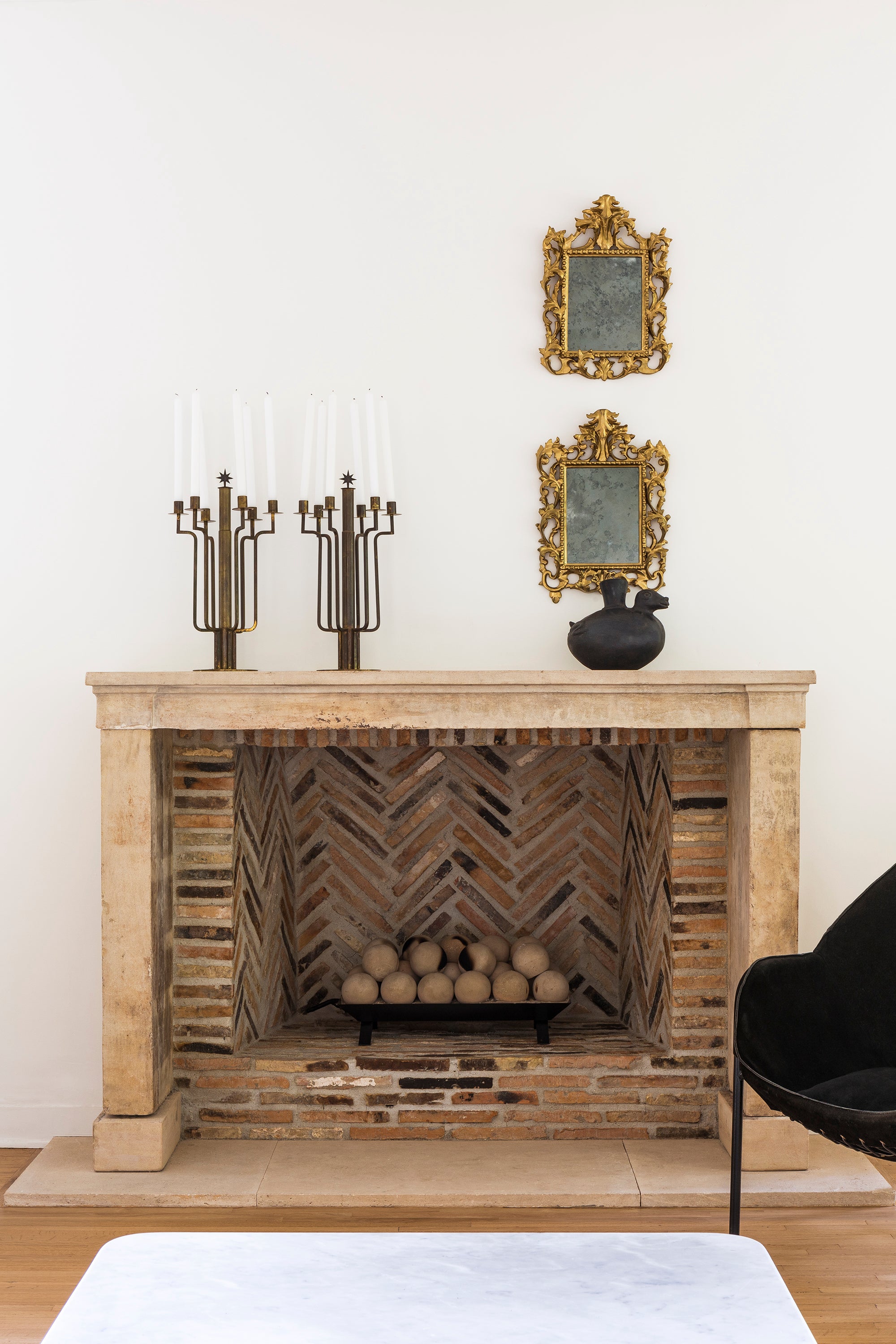 A pair of candelabras and a pair of mirrors sit above a rustic fireplace in Nate Berkus and Jeremiah Brent's Hancock Park estate.
