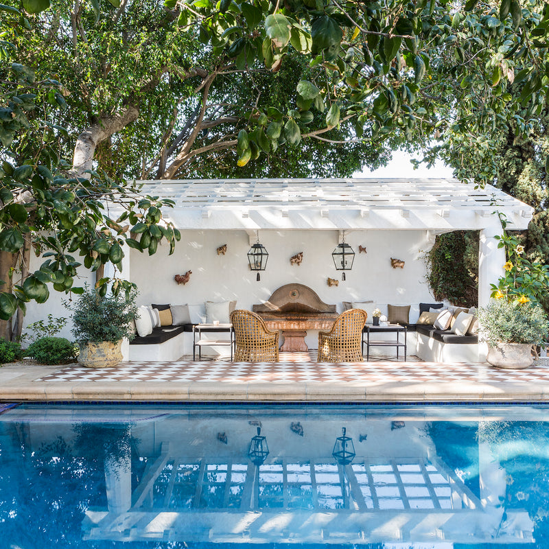 A spa-like pool scene with a cozy outdoor sitting area beneath a covered pergola, designed by Nate Berkus and Jeremiah Brent for their Hancock Park estate.