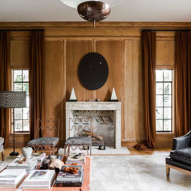 A wood-paneled living area of warm tones, clean lines, and collected furnishings by Nate Berkus and Jeremiah Brent.