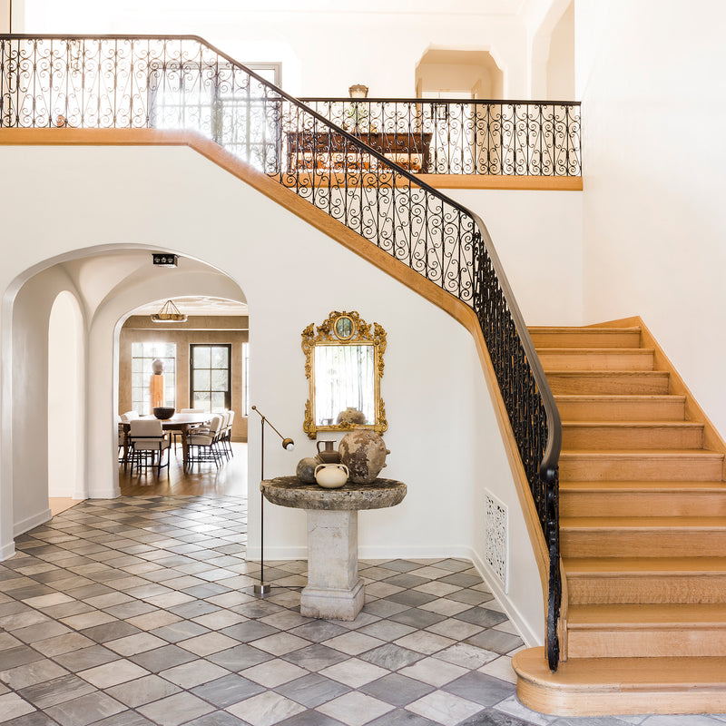The entryway of Hancock Park, a 1928 Spanish Colonial by Nate Berkus Associates, showcases its original charms with checkered floors and an impressive staircase.