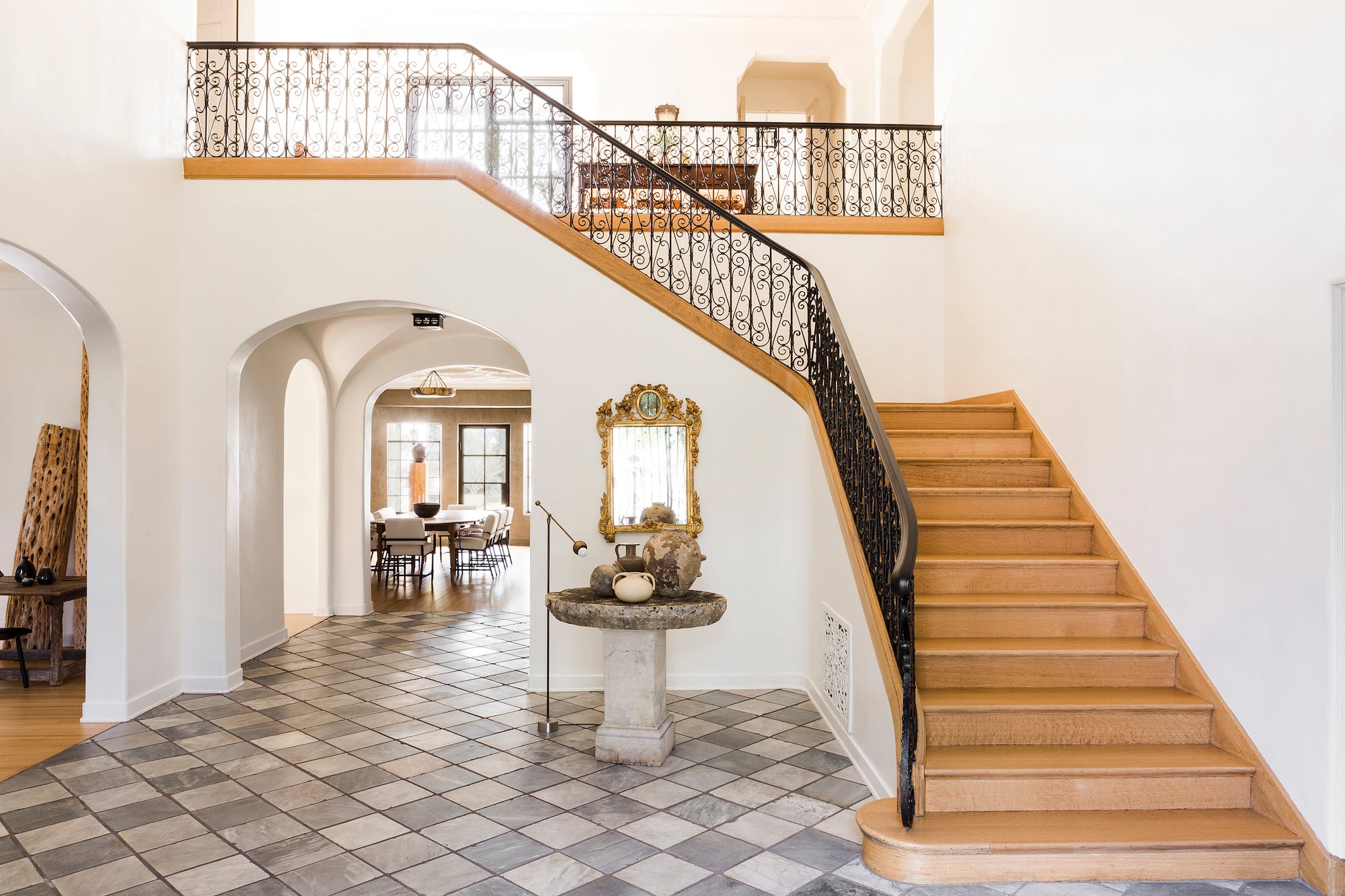 The entryway of Hancock Park, a 1928 Spanish Colonial by Nate Berkus Associates, showcases its original charms with checkered floors and an impressive staircase.