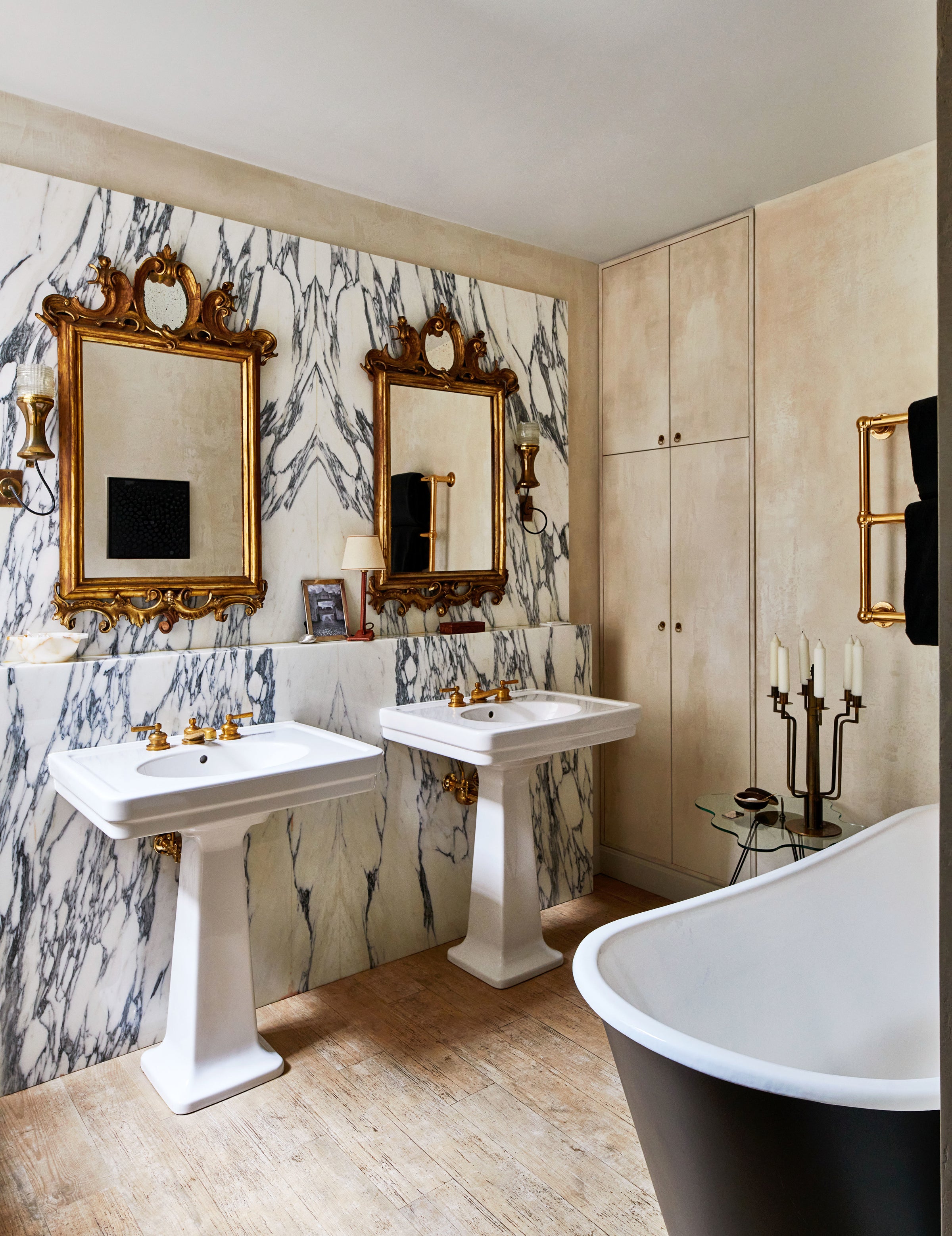 This Manhattan bathroom by Nate Berkus and Jeremiah Brent features floor-to-ceiling marble, ornate mirrors, pedestal sinks, and standalone tub.