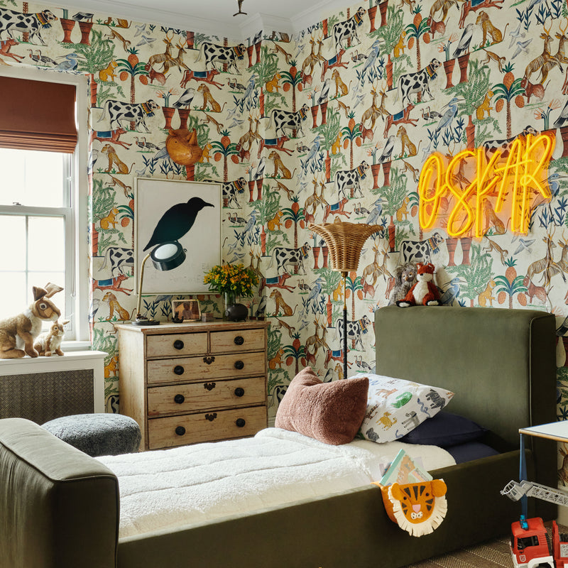 This colorful room, designed by Nate Berkus and Jeremiah Brent for their son, features illustrated wallpaper, an upholstered bed, and statement lighting.
