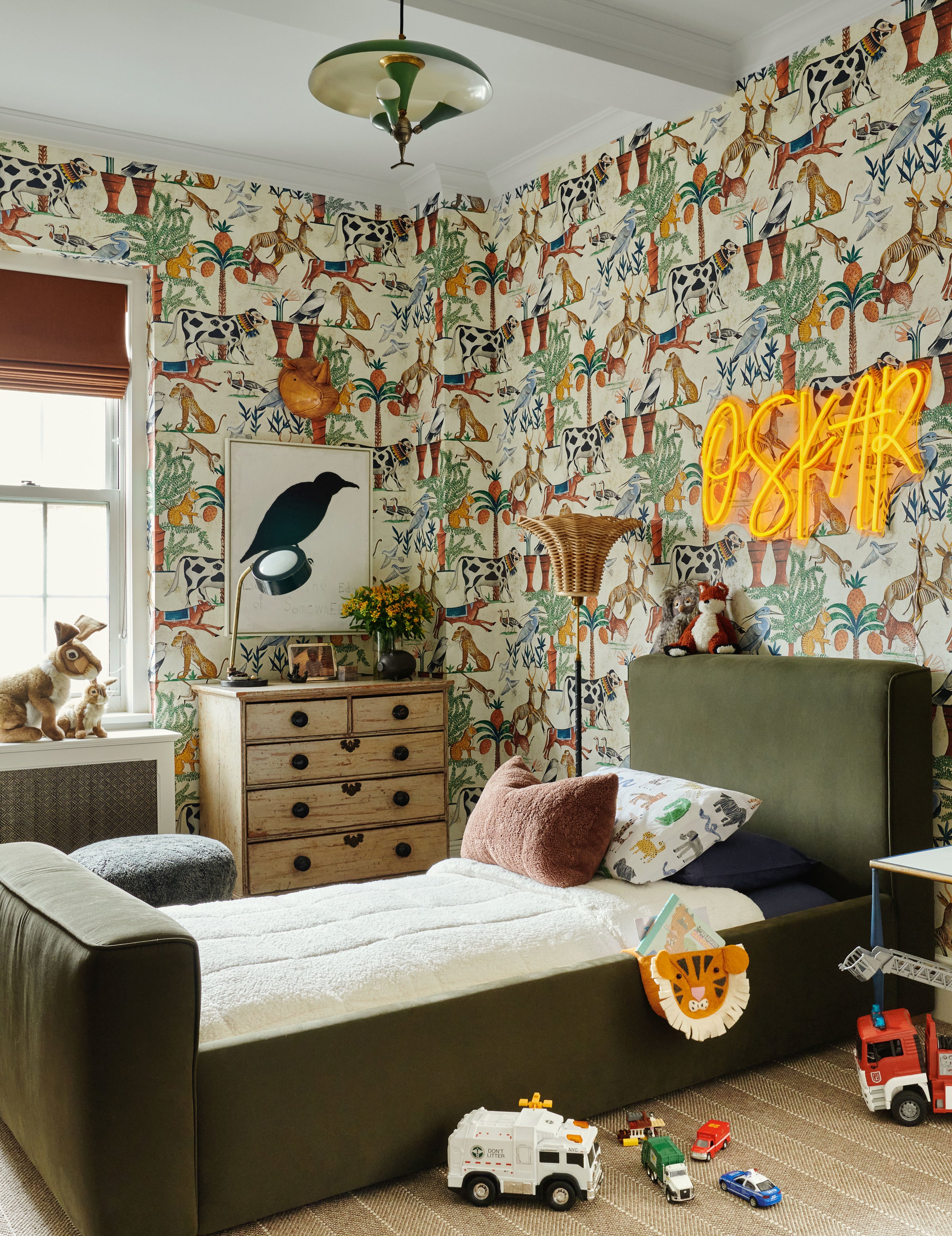 This colorful room, designed by Nate Berkus and Jeremiah Brent for their son, features illustrated wallpaper, an upholstered bed, and statement lighting.