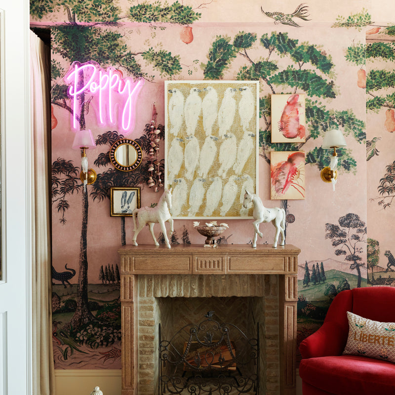 A vignette, designed by Nate Berkus and Jeremiah Brent for their daughter's room, with an original fireplace, curated wall art, and a custom neon sign.