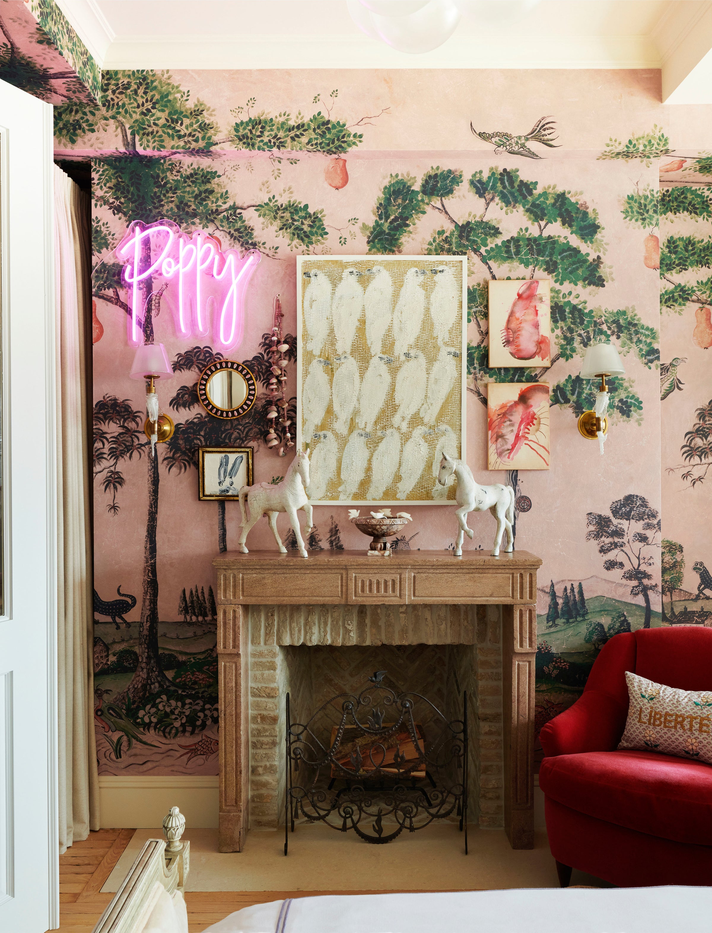 A vignette, designed by Nate Berkus and Jeremiah Brent for their daughter's room, with an original fireplace, curated wall art, and a custom neon sign.